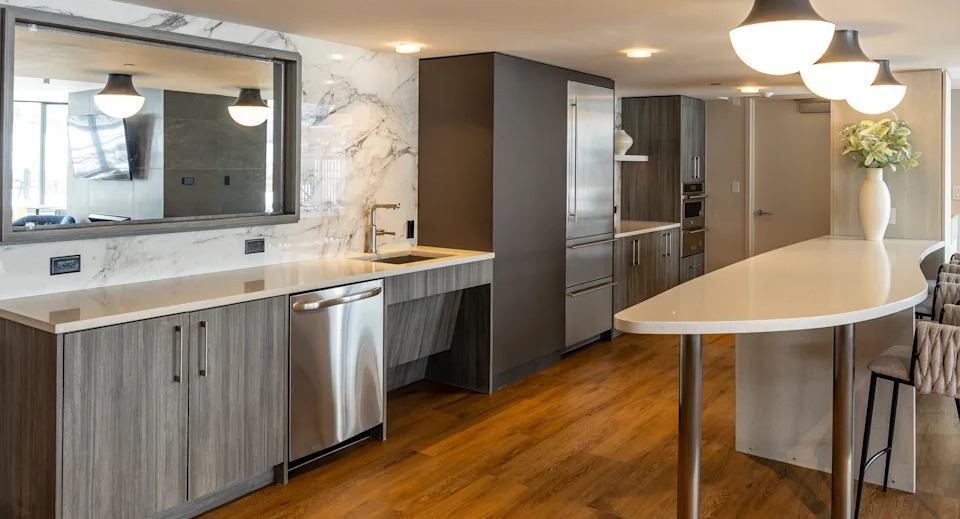 Sophisticated resident lounge with a full kitchen, long bar with seating, and a large mirror, ideal for social gatherings at Kingsbury Plaza in Chicago