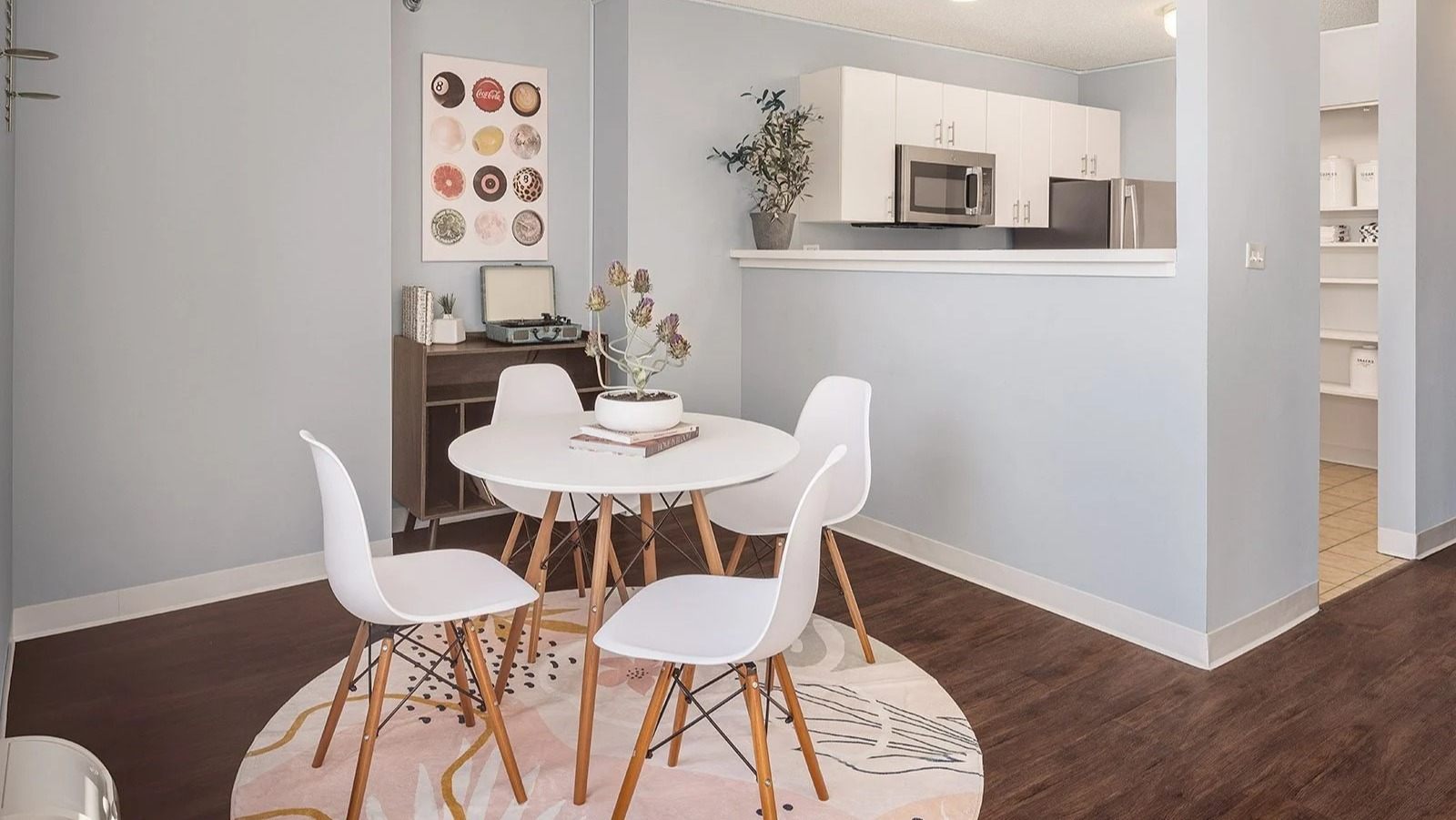 Bright apartment dining area with a round table and a compact, functional kitchen visible in the background at Lake Shore Plaza Chicago