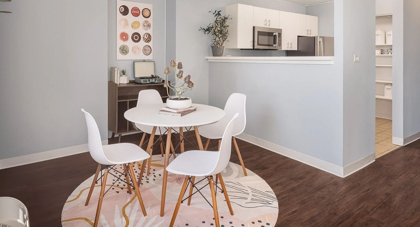 Bright apartment dining area with a round table and a compact, functional kitchen visible in the background at Lake Shore Plaza Chicago