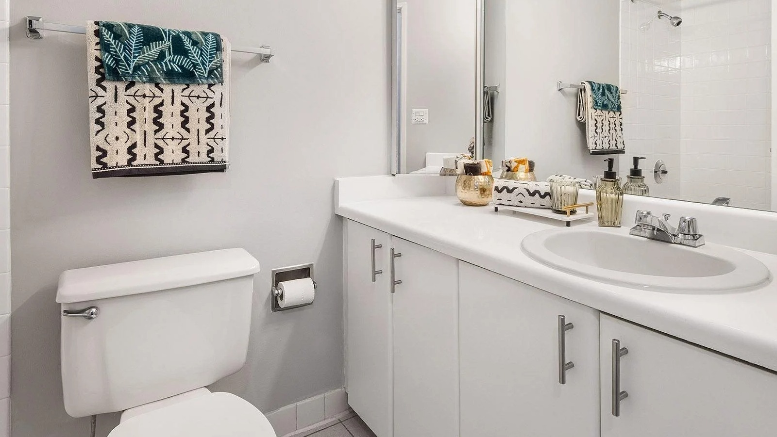 Bright apartment bathroom at Lake Shore Plaza in Chicago, with a spacious vanity, large mirror, and clean white tile