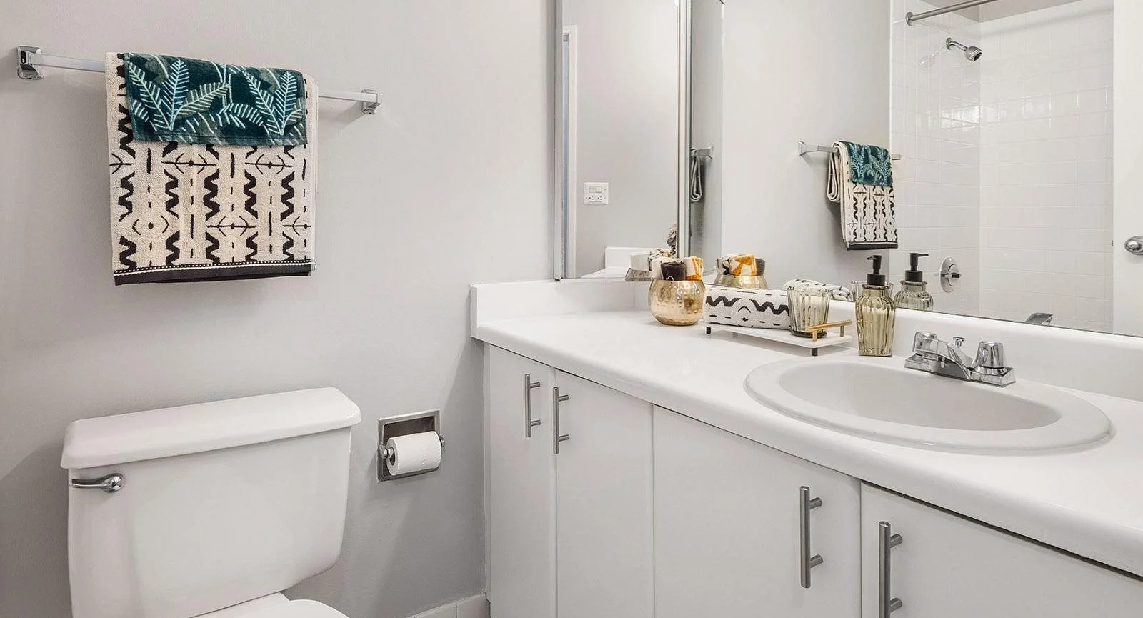 Bright apartment bathroom at Lake Shore Plaza in Chicago, with a spacious vanity, large mirror, and clean white tile