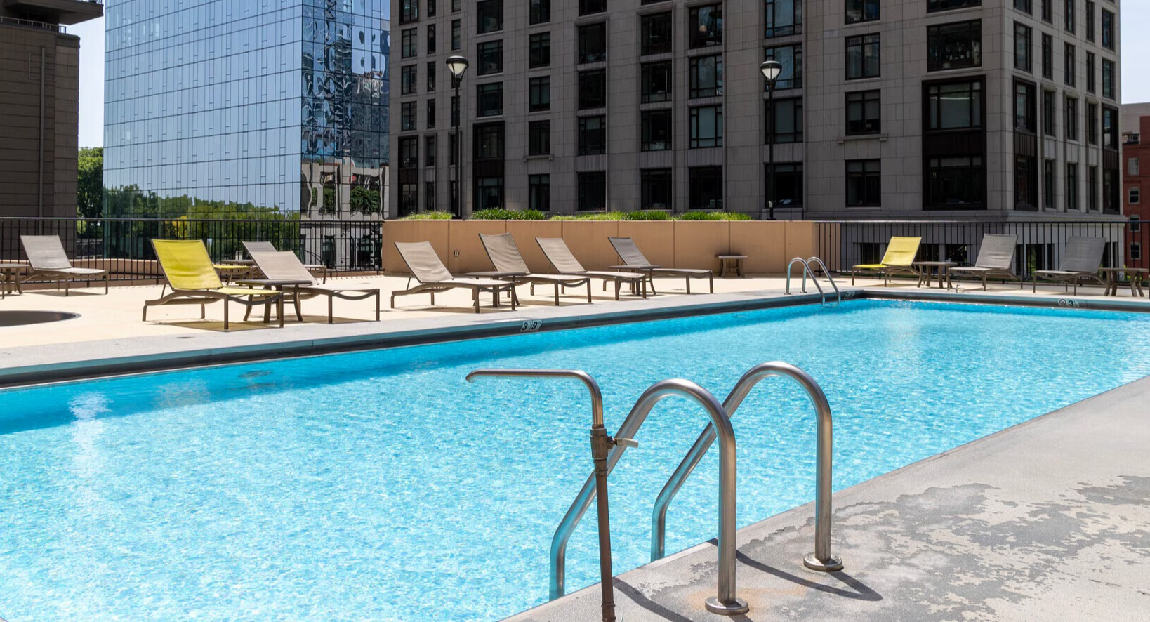 Beautiful outdoor swimming pool and sundeck with lounge chairs and privacy walls at Lake Shore Plaza apartments in Chicago