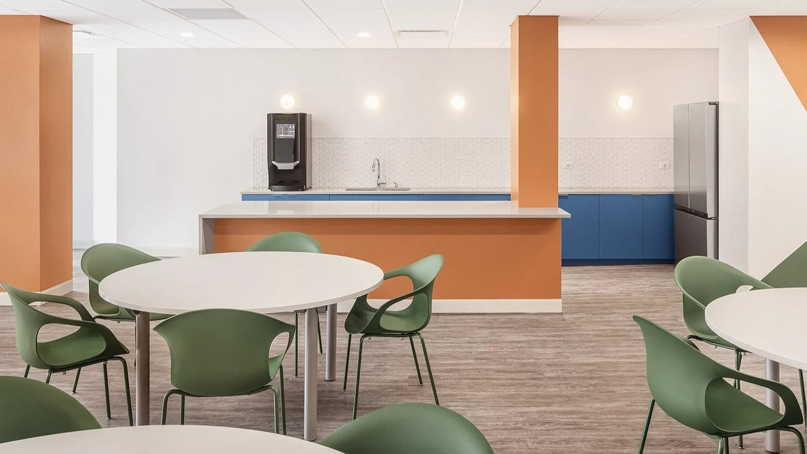 Modern community kitchen and cafe area with dining tables and colorful accents at Lake Shore Plaza Chicago