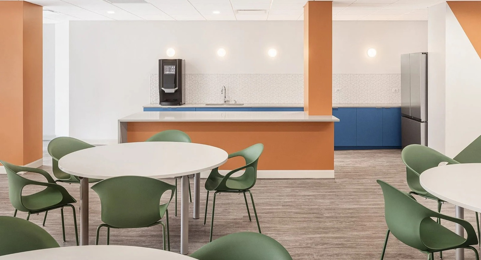 Modern community kitchen and cafe area with dining tables and colorful accents at Lake Shore Plaza Chicago