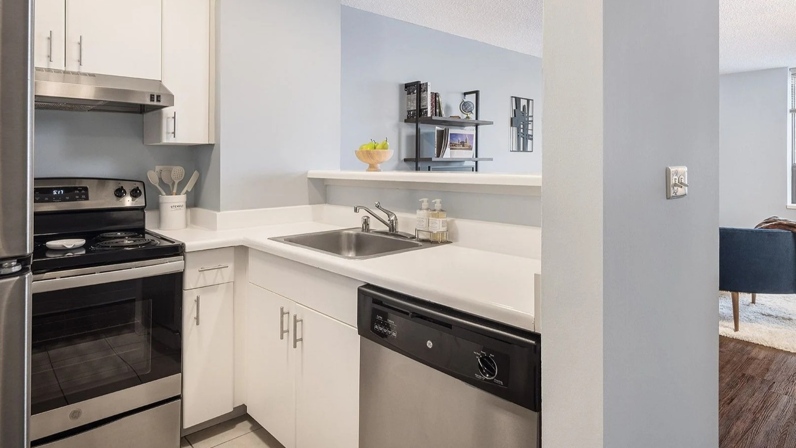 Modern apartment kitchen at Lake Shore Plaza in Chicago, with stainless steel appliances and an open view into the inviting living area