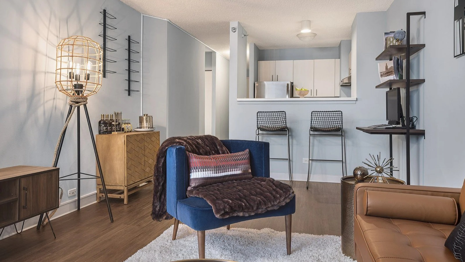Comfortable apartment lounge area at Lake Shore Plaza in Chicago, with a stylish sofa, accent chairs, and a view of the modern kitchen