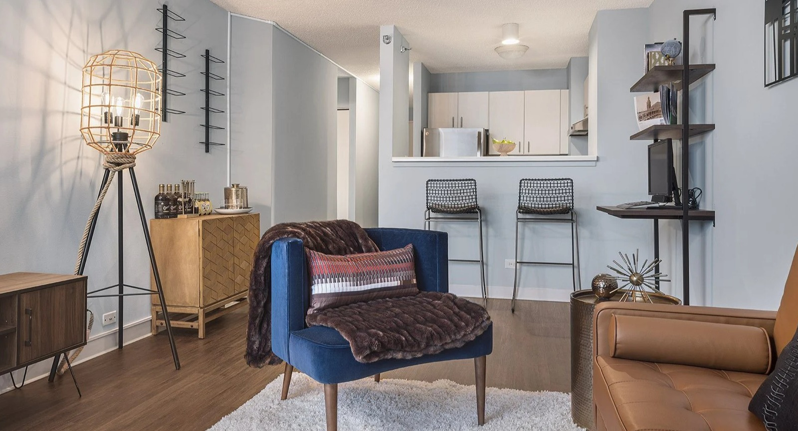 Comfortable apartment lounge area at Lake Shore Plaza in Chicago, with a stylish sofa, accent chairs, and a view of the modern kitchen