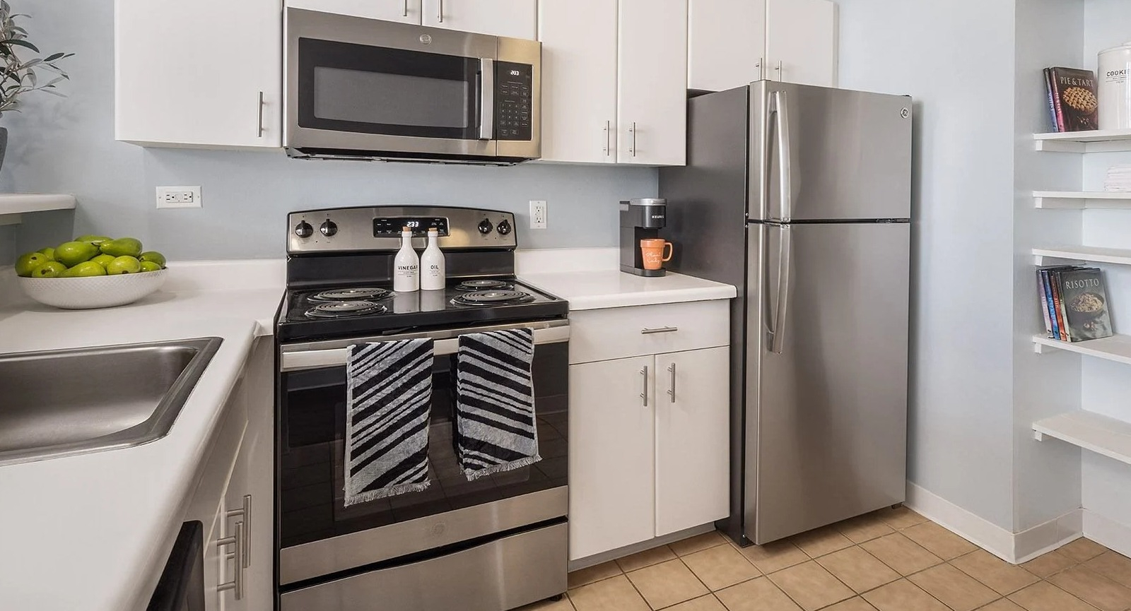 Modern apartment kitchen at Lake Shore Plaza in Chicago, with stainless steel appliances, white cabinetry, and convenient shelving