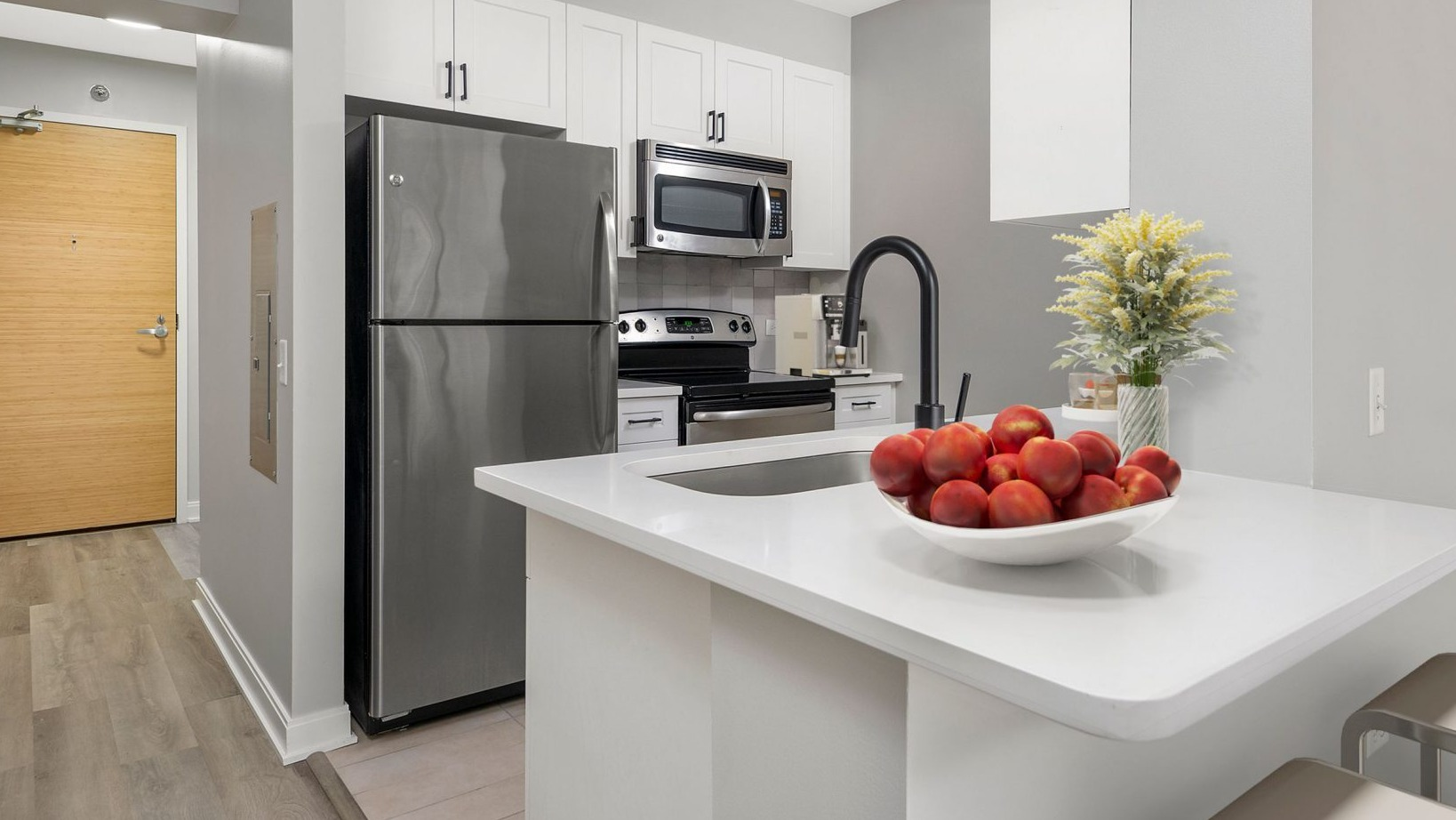 Contemporary kitchen at Lake & Wells with stainless steel appliances, breakfast bar, and entryway visible