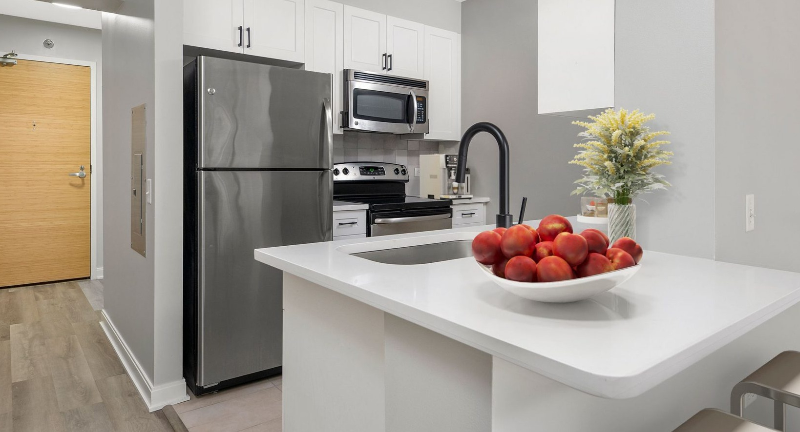 Contemporary kitchen at Lake & Wells with stainless steel appliances, breakfast bar, and entryway visible