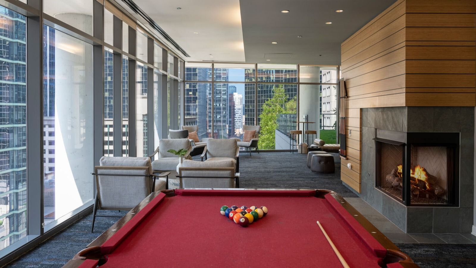 Lake & Wells game room featuring a billiards table, cozy fireplace, and stunning city views from large windows