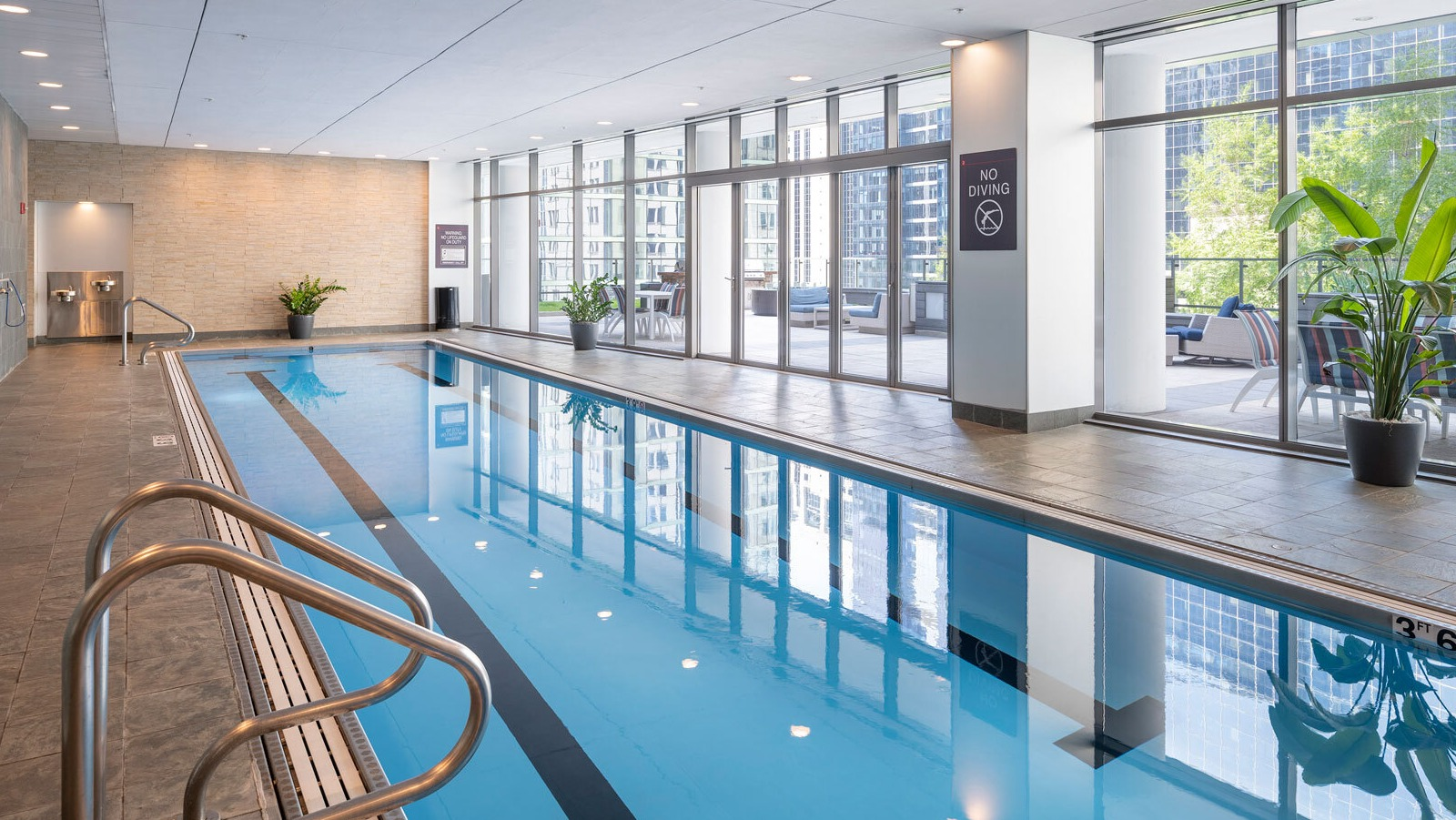 Lake & Wells indoor swimming pool with floor-to-ceiling windows, inviting residents to relax and swim with city views