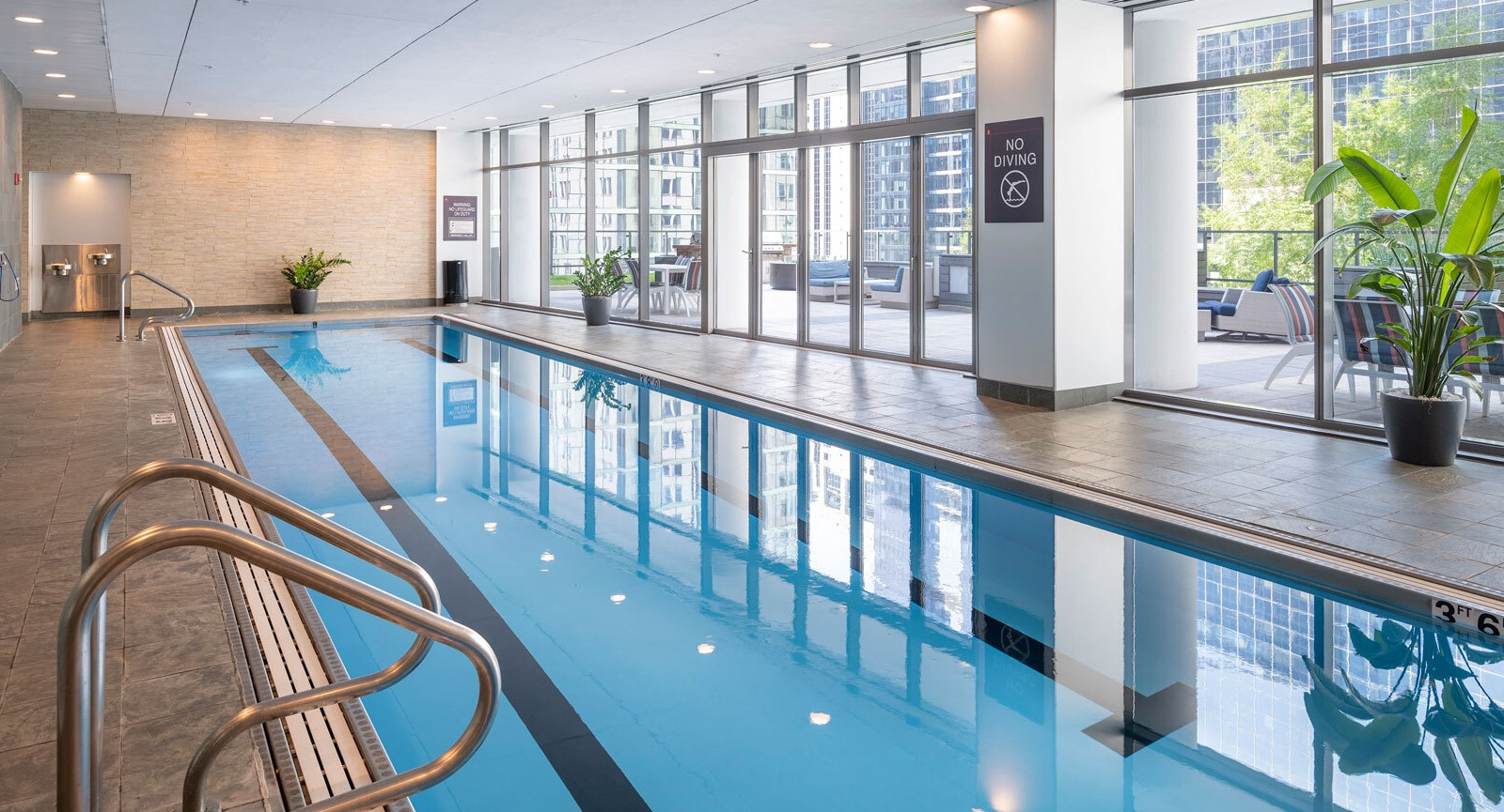 Lake & Wells indoor swimming pool with floor-to-ceiling windows, inviting residents to relax and swim with city views