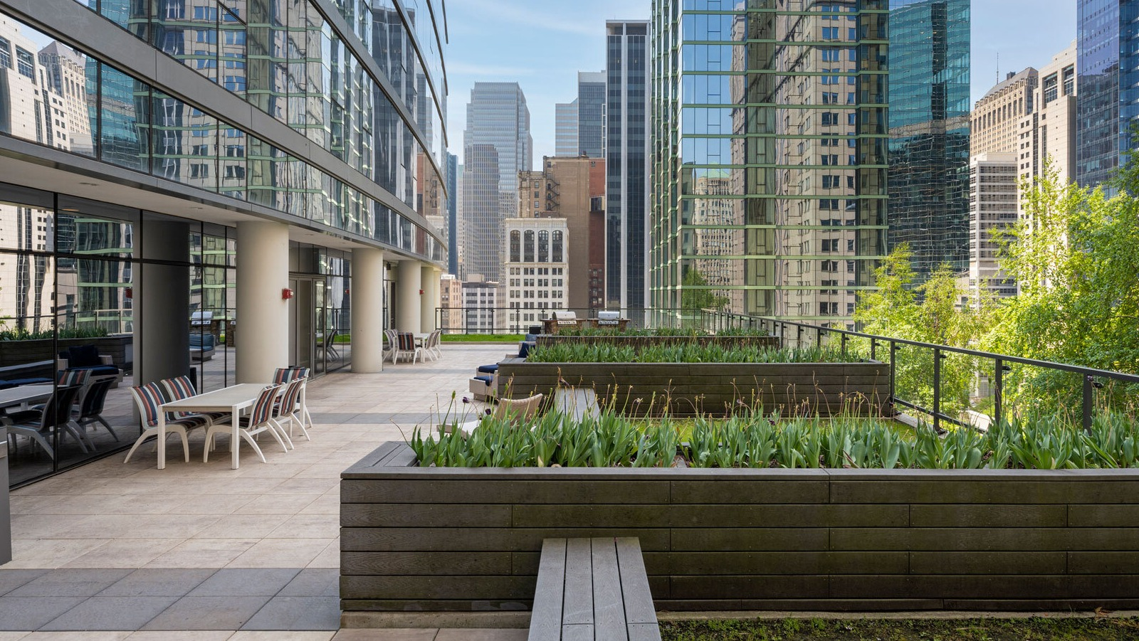 Lake & Wells outdoor patio with seating and planters, offering a refreshing urban oasis amidst city buildings