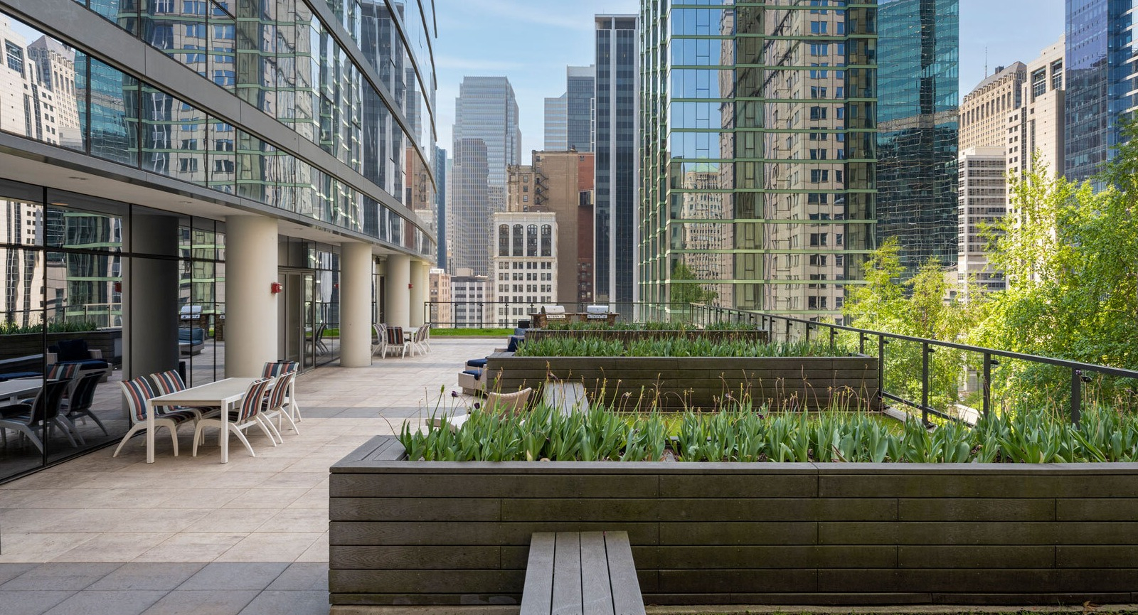 Lake & Wells outdoor patio with seating and planters, offering a refreshing urban oasis amidst city buildings