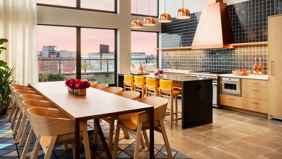 Sleek community demonstration kitchen with a spacious island, stainless steel appliances, and ample seating at Landmark West Loop