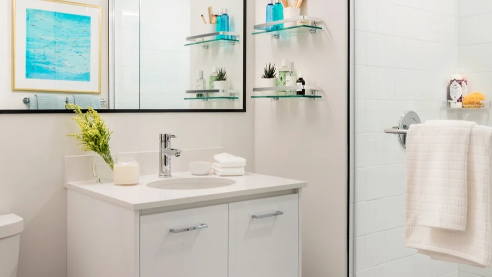 Modern apartment bathroom at Landmark West Loop in Chicago, featuring a spacious glass shower, sleek vanity, and dark hexagonal floor tiles