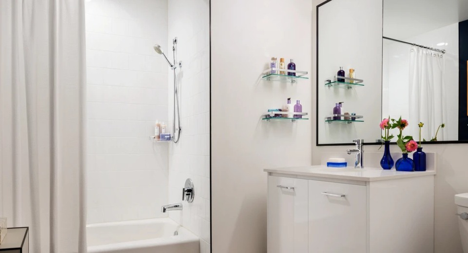 Modern apartment bathroom at Landmark West Loop in Chicago, featuring a clean white bathtub with shower and a stylish vanity