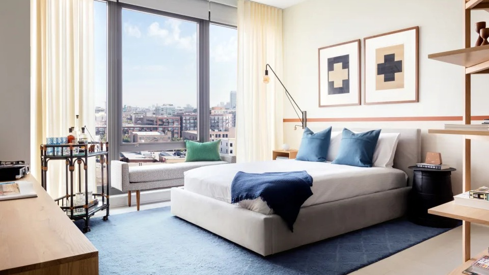 Bright and inviting bedroom with a large window offering city views, featuring modern furniture at Landmark West Loop in Chicago