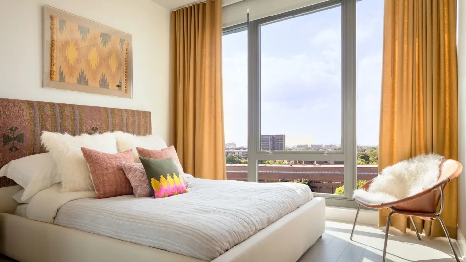 Elegant apartment bedroom at Landmark West Loop in Chicago, featuring a large bed, stylish decor, and floor-to-ceiling windows with ample natural light