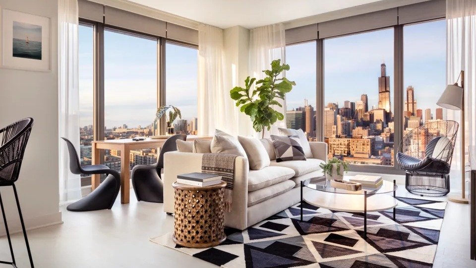 Spacious corner living room at Landmark West Loop in Chicago, featuring comfortable seating, modern rug, and panoramic city views