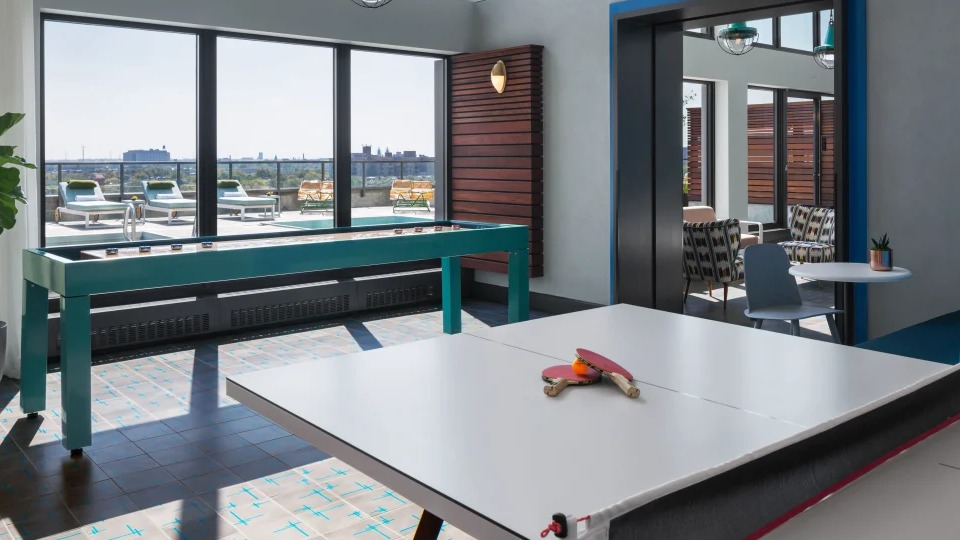 Fun game room featuring a shuffleboard table, ping pong table, and large windows at Landmark West Loop apartments in Chicago