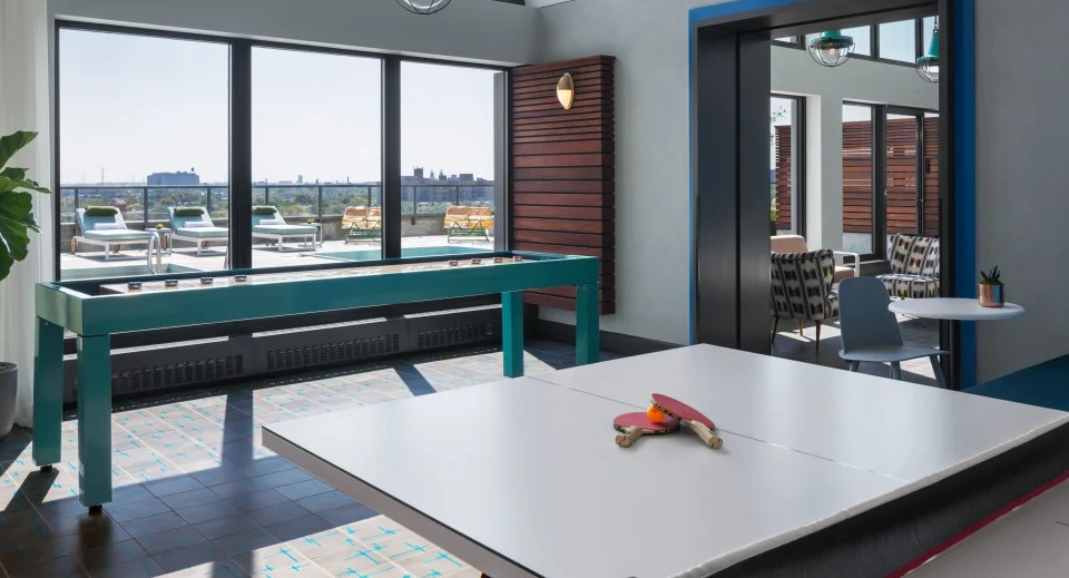 Fun game room featuring a shuffleboard table, ping pong table, and large windows at Landmark West Loop apartments in Chicago