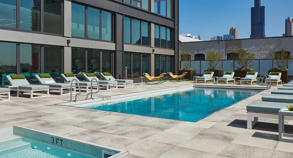 Inviting outdoor pool and hot tub area with sun loungers and city skyline views at Landmark West Loop apartments in Chicago