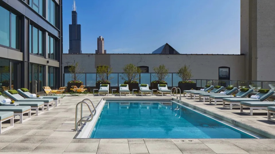Outdoor swimming pool deck with comfortable lounge chairs and a stunning Chicago city skyline view at Landmark West Loop