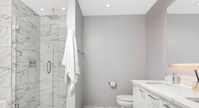 Elegant bathroom with a double vanity, large mirror, and a spacious walk-in shower at Left Bank apartments in Chicago