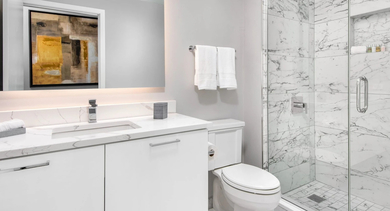Luxurious bathroom with a modern vanity, large mirror, and a marble-tiled walk-in shower at Left Bank apartments in Chicago