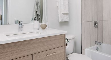 Modern bathroom with a wood-finish vanity, large mirror, and a clean tub/shower combination at Left Bank apartments in Chicago