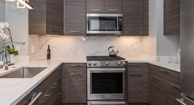 Sophisticated kitchen featuring dark wood cabinets, white marble countertops, and stainless steel appliances at Left Bank in Chicago