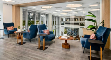 Upper level lounge area with comfortable blue armchairs and views into other community spaces at Left Bank apartments in Chicago