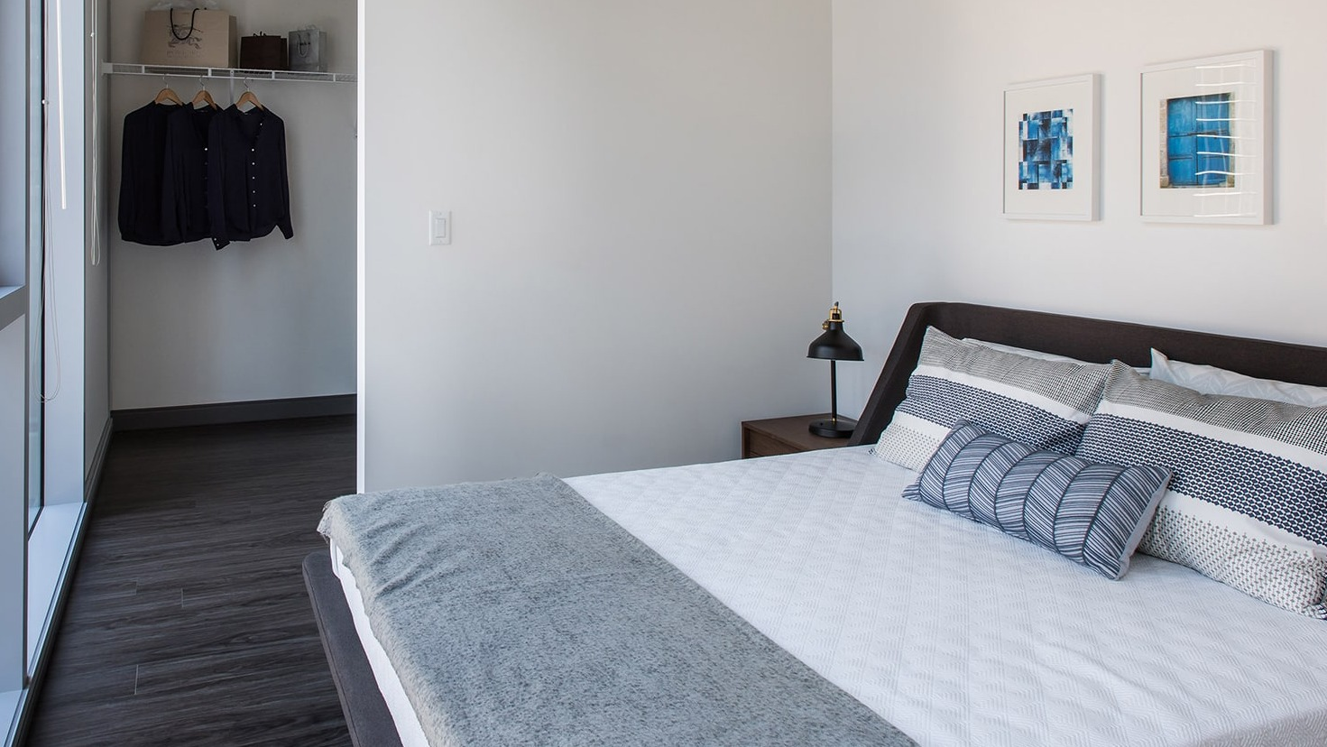 Cozy bedroom with large windows and an open walk-in closet, offering city views at Linea Apartments in Chicago