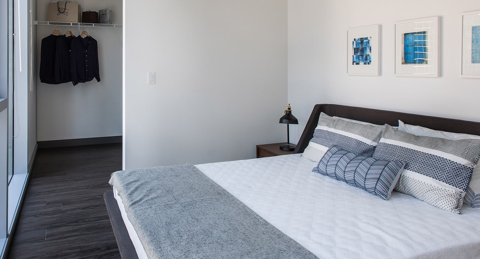 Cozy bedroom with large windows and an open walk-in closet, offering city views at Linea Apartments in Chicago