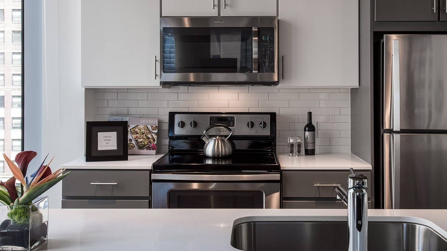 Close-up of a modern kitchen countertop with sink and appliances, featuring city views at Linea Apartments in Chicago