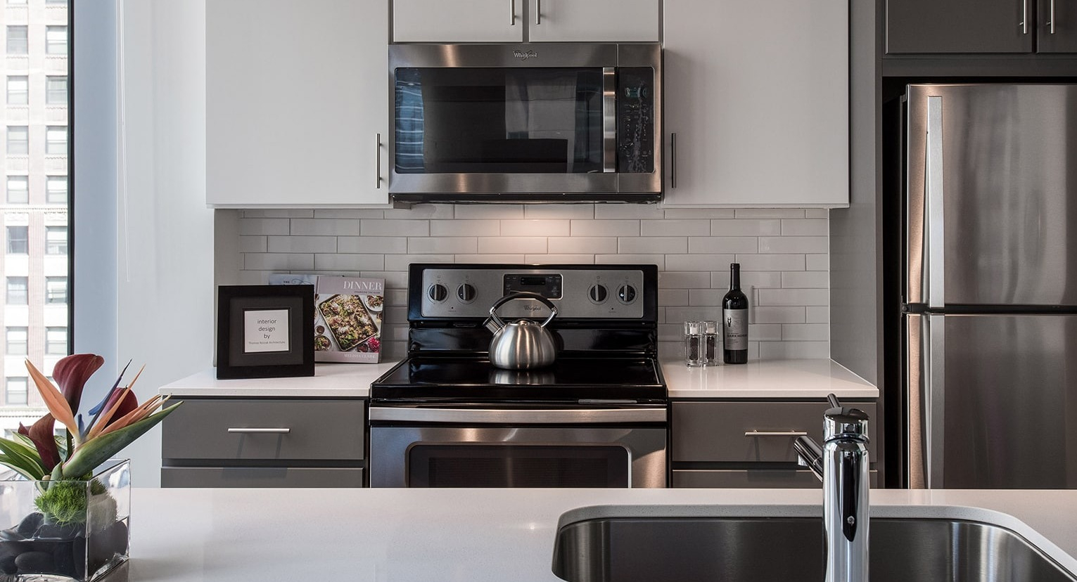 Close-up of a modern kitchen countertop with sink and appliances, featuring city views at Linea Apartments in Chicago