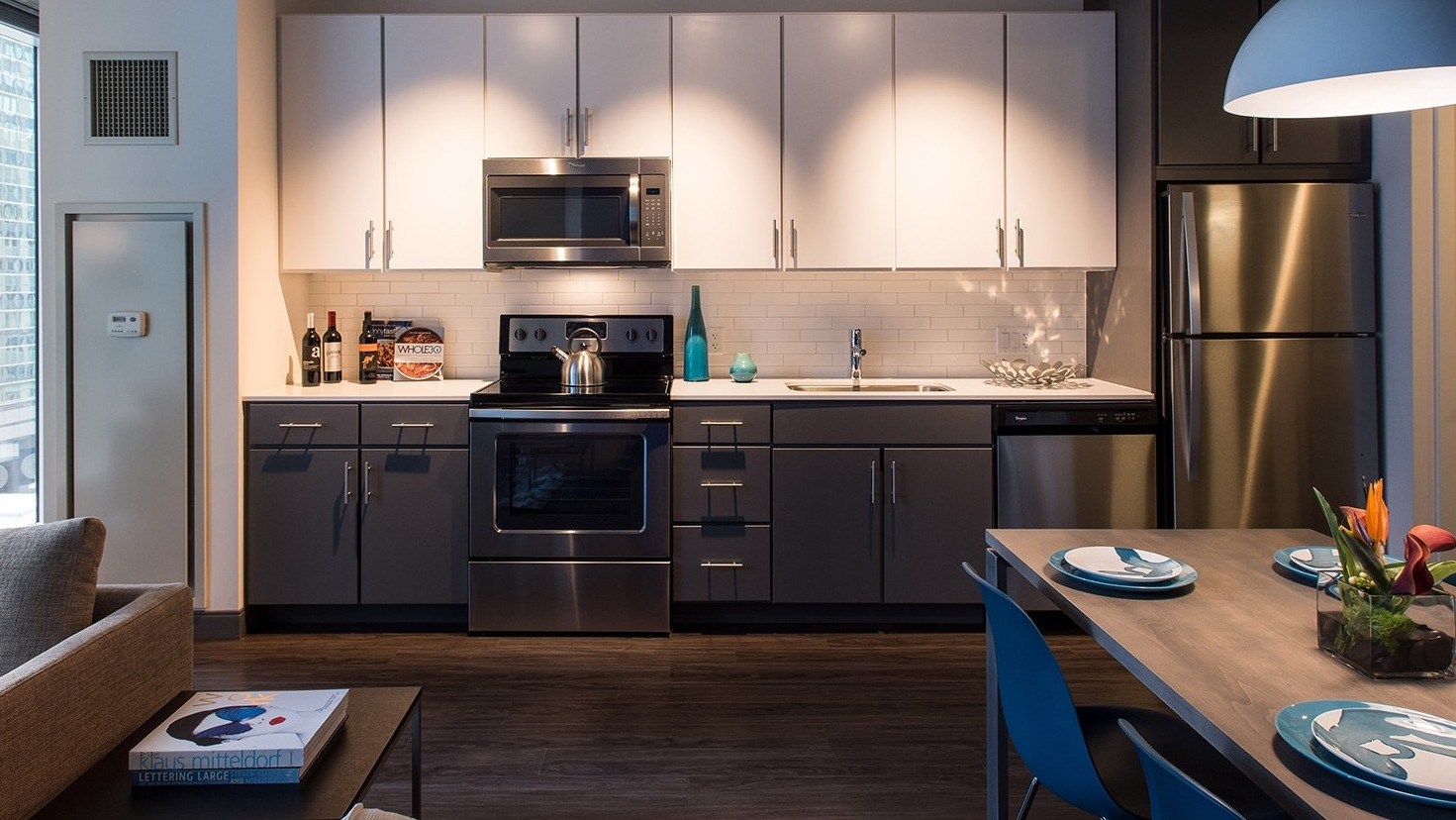 Modern kitchen with white and grey cabinetry, stainless steel appliances, and adjacent dining area at Linea Apartments in Chicago