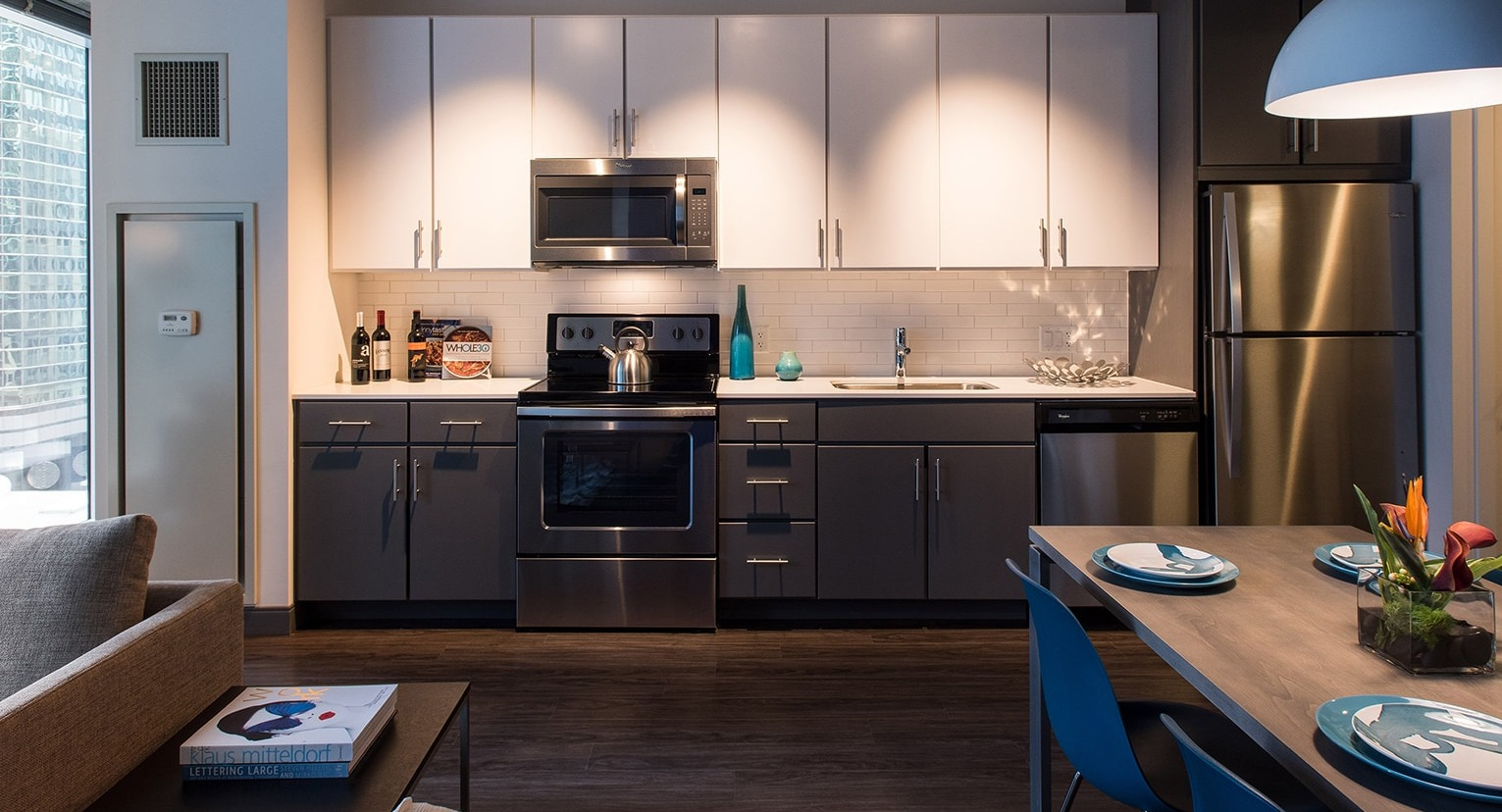 Modern kitchen with white and grey cabinetry, stainless steel appliances, and adjacent dining area at Linea Apartments in Chicago