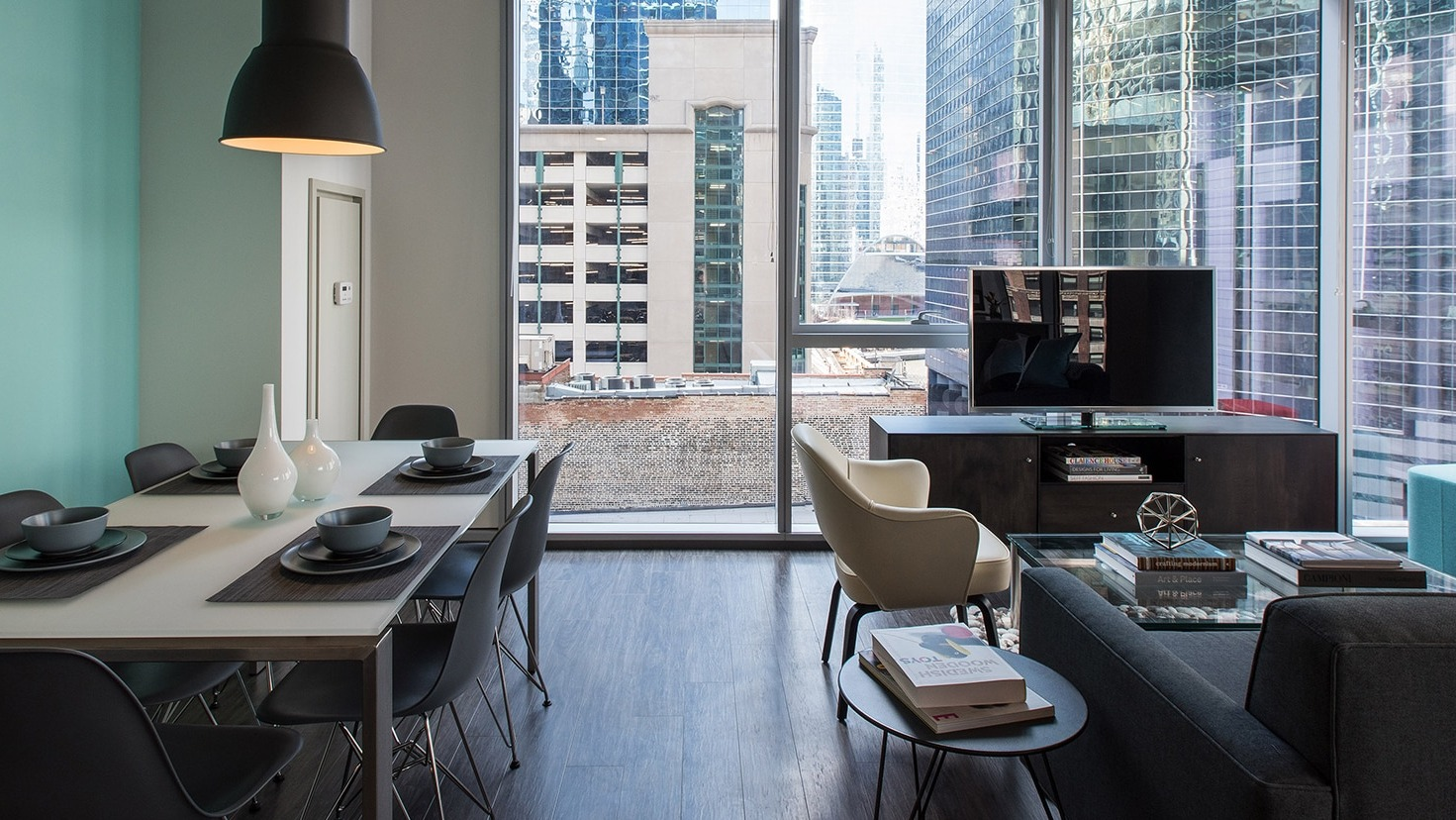 Open-plan living and dining area with modern furniture, large windows, and stunning city views at Linea Apartments in Chicago