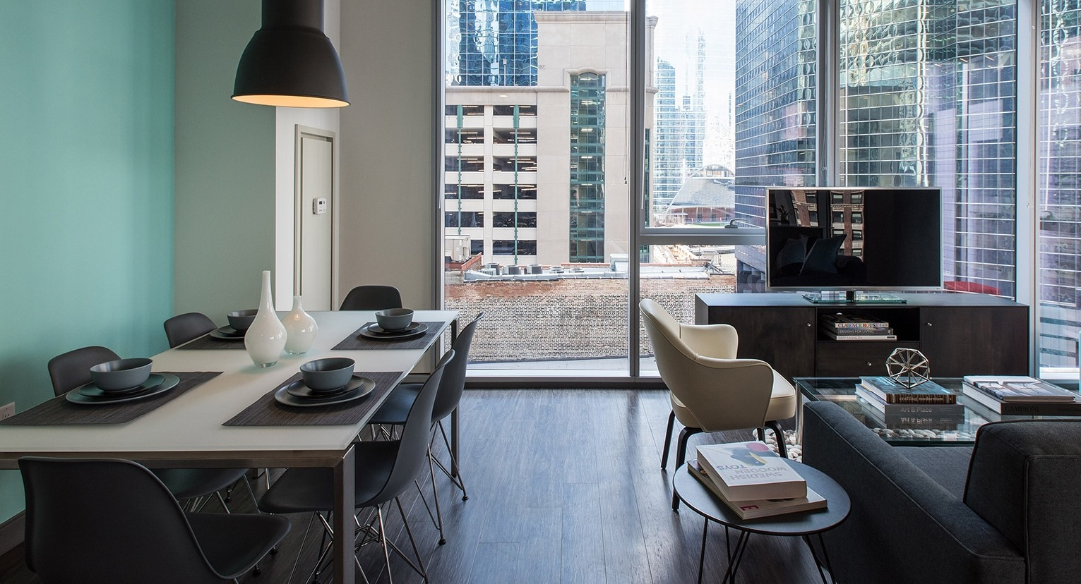 Open-plan living and dining area with modern furniture, large windows, and stunning city views at Linea Apartments in Chicago