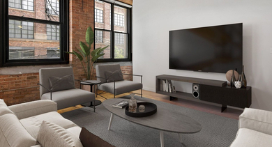 Industrial-chic living room at The Lofts at Gin Alley in Chicago, featuring a large TV, comfortable sofas, and exposed brick walls