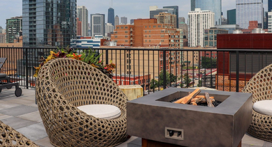Inviting rooftop lounge at The Lofts at Gin Alley in Chicago, featuring a fire pit, comfortable seating, and panoramic city views