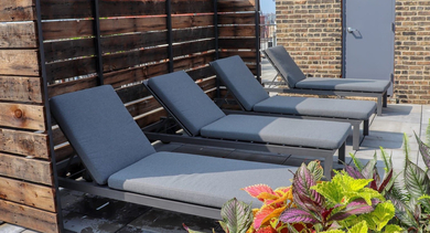 Serene rooftop sun deck at The Lofts at Gin Alley in Chicago, featuring comfortable loungers, privacy screens, and lush plants