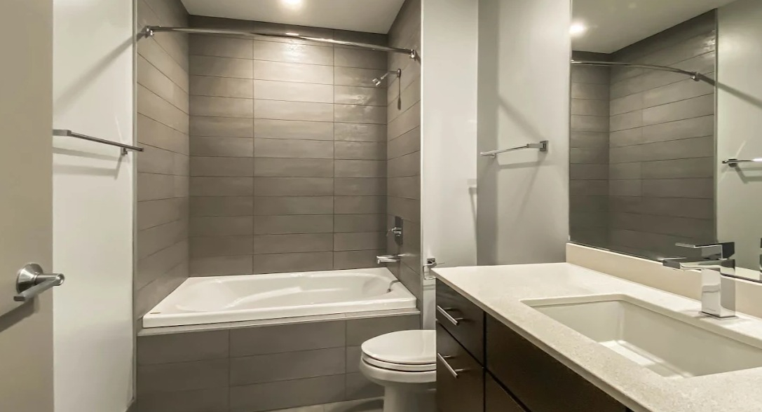 Contemporary bathroom with a spacious vanity, sleek fixtures, and a shower-tub combination with grey tile at Lofts at River East in Chicago