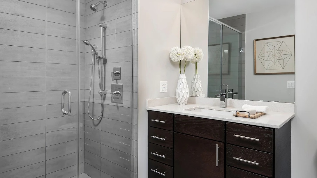 Modern bathroom featuring a spacious walk-in glass shower, single vanity, and contemporary gray tile at Lofts at River East in Chicago