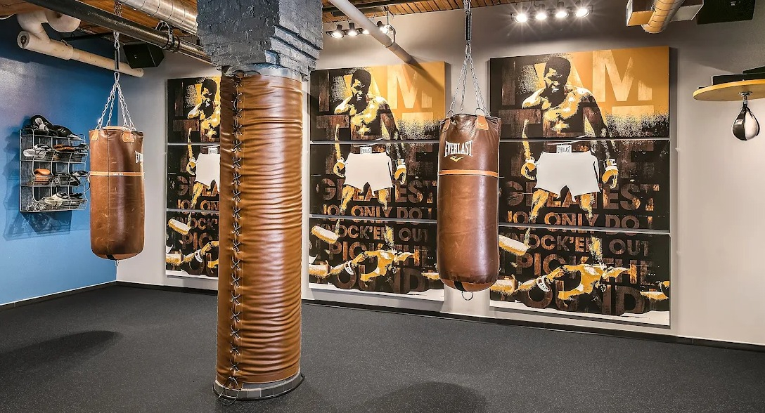 Dedicated boxing gym area with punching bags, speed bag, and inspiring wall art of Muhammad Ali at Lofts at River East in Chicago