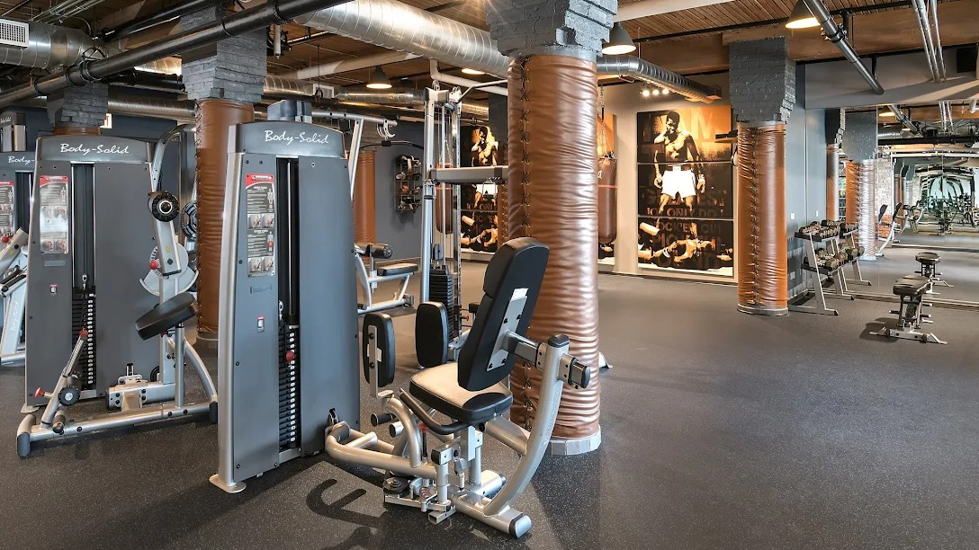 Expansive fitness center with a variety of weight machines, free weights, and industrial-chic design elements at Lofts at River East in Chicago