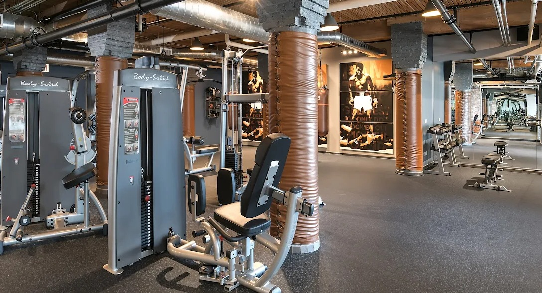 Expansive fitness center with a variety of weight machines, free weights, and industrial-chic design elements at Lofts at River East in Chicago